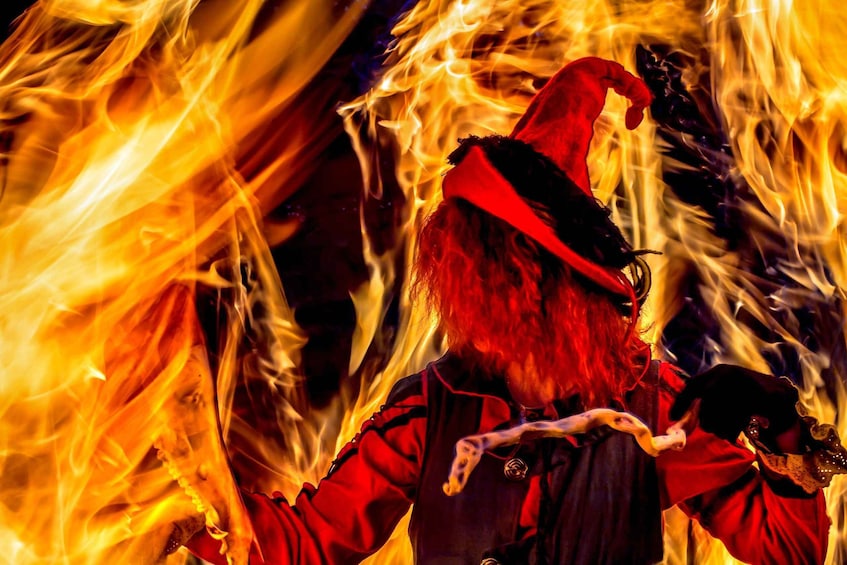 A person with a red hat and red clothing amidst flames. 3