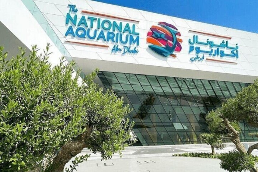 The National Aquarium building with a modern glass facade and signage in multiple languages. 1