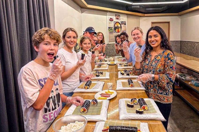 En gruppe mennesker laver sushi ved en disk. 1