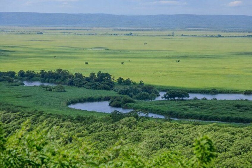 A vast savanna landscape with a winding river, dense greenery, and distant hills. 5