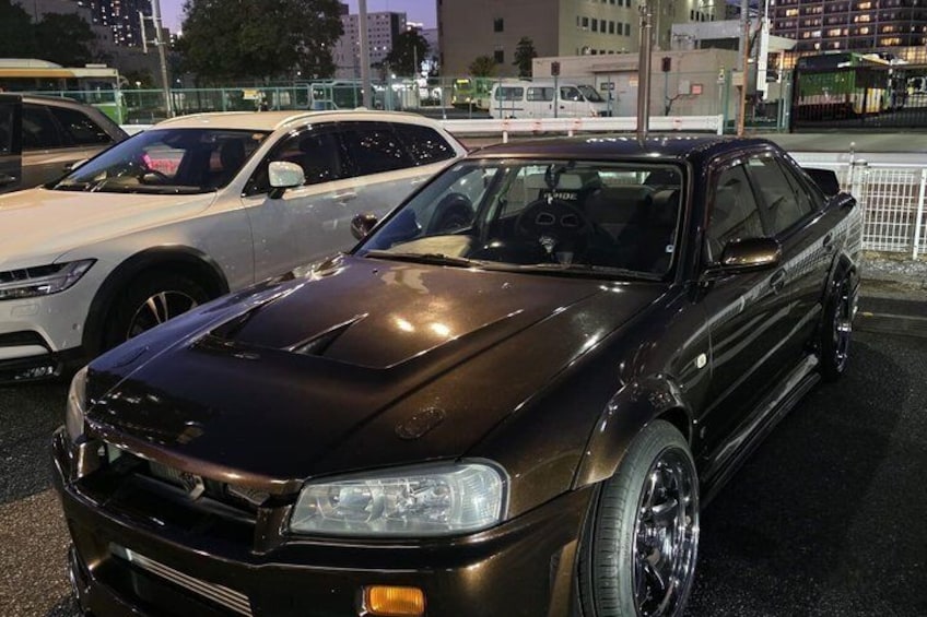 A dark-colored car parked in a lot with other vehicles. 4