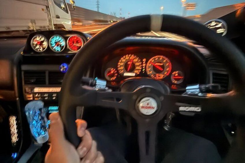 A vehicle's dashboard with a steering wheel, speedometer, tachometer, and various gauges. 3