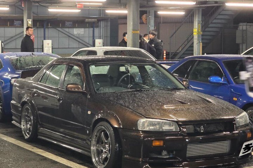 A black car with a spoiler parked in a garage. 2