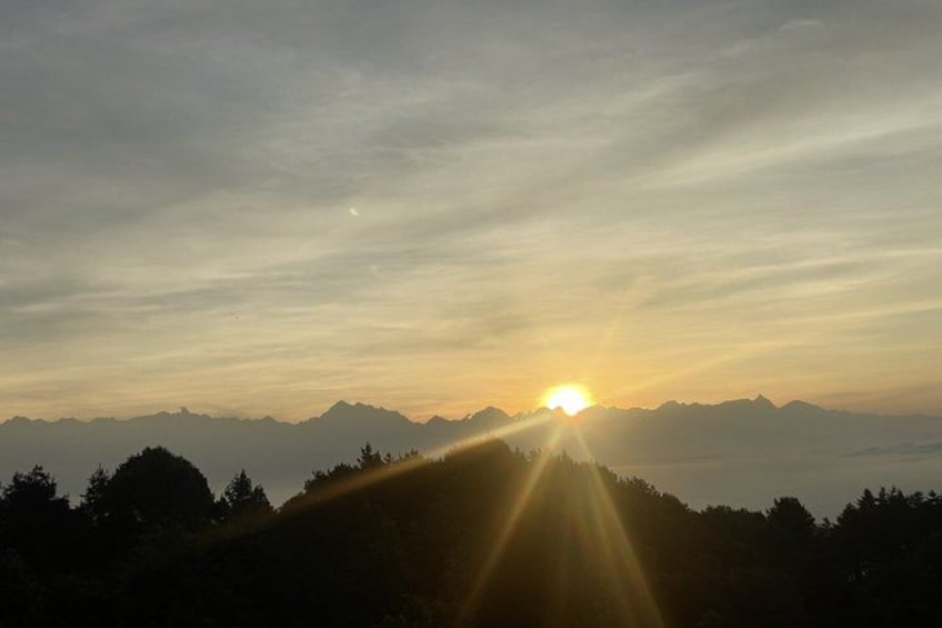 A sunrise over a mountain range with rays of sunlight piercing through the clouds. 3