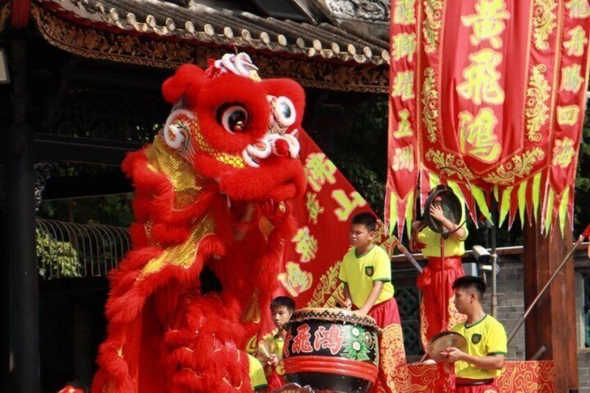 A red lion dance costume, performers in yellow, and traditional Chinese banners. 1