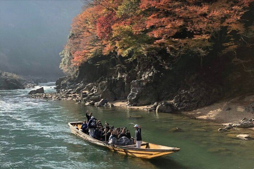 A group of people in a small boat on a river surrounded by autumn-colored trees. 5