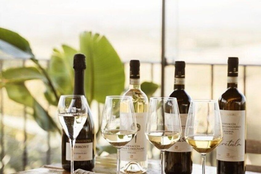 Bottles of wine and glasses on a table with a view of greenery in the background. 1