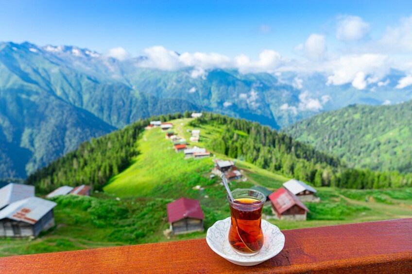 A mountainous landscape with a clear sky, a wooden railing, and a glass of tea. 4
