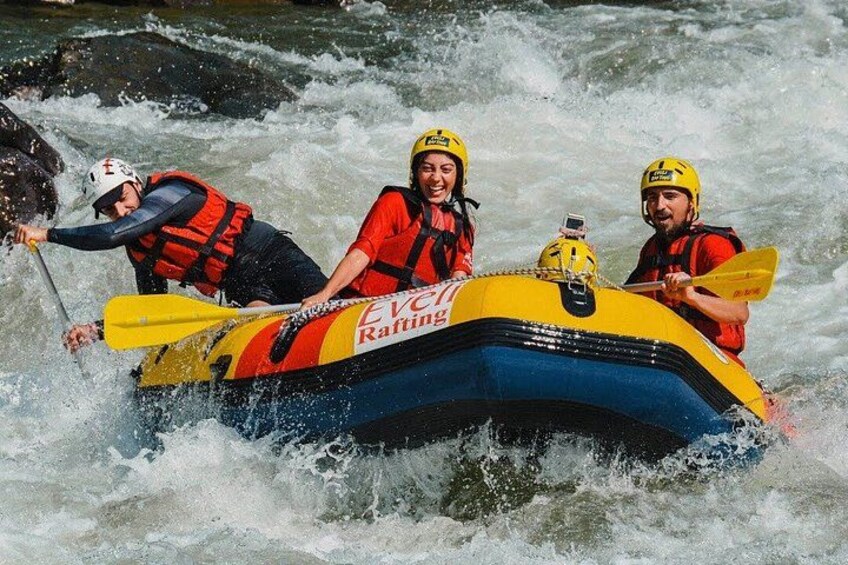 Three people in a yellow and blue raft navigating a river. 5