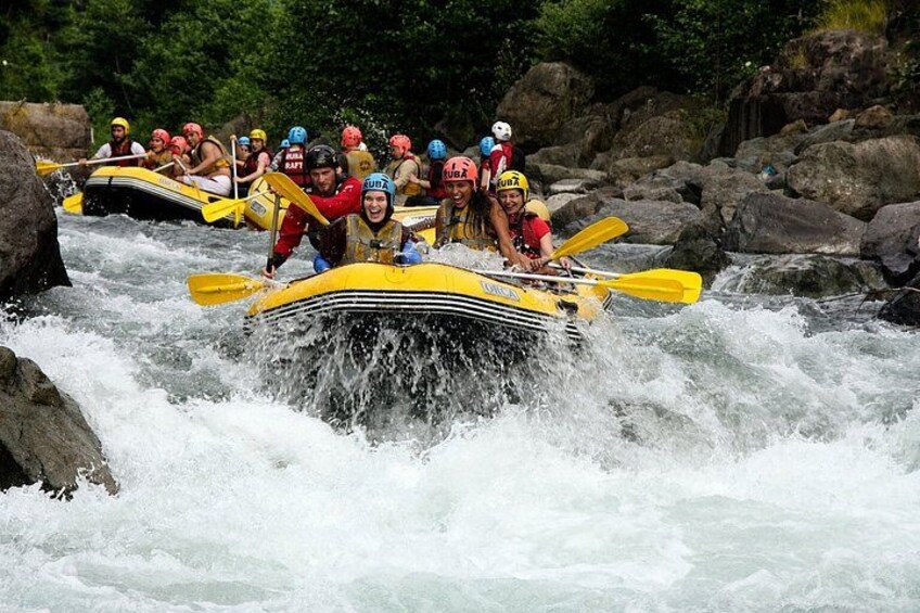 A group of people in a yellow raft navigating a river with rapids. 2