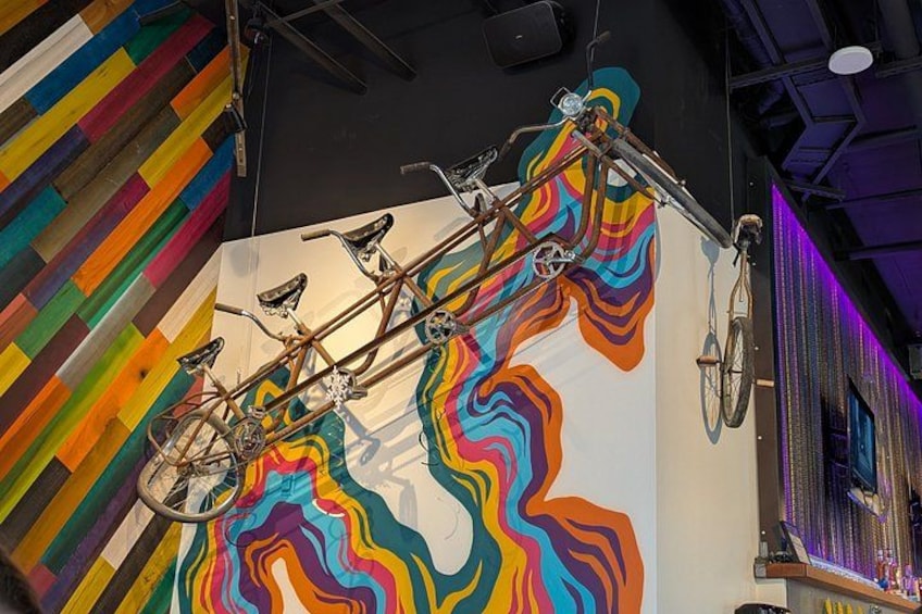 A bicycle leaning against a colorful mural with a striped wall in the background. 2