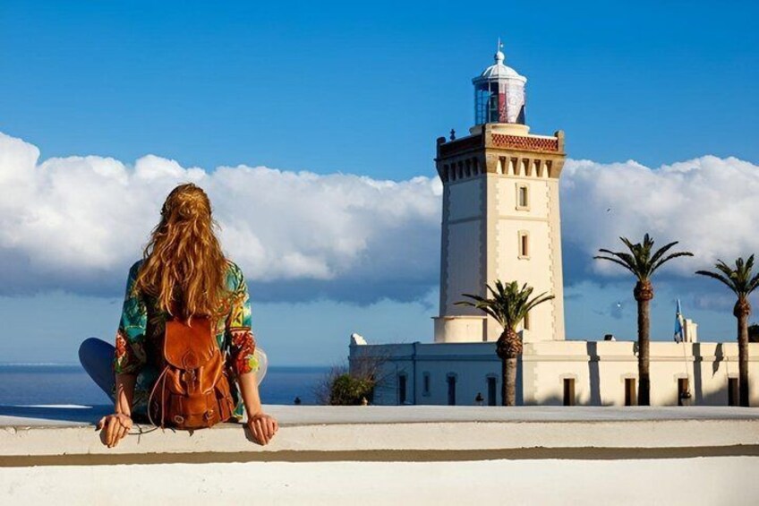 A person sitting on a ledge with a lighthouse in the background. 4