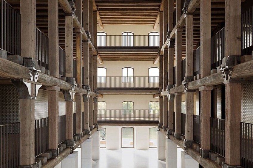 A spacious interior with wooden beams, balconies, and a reflective floor. 4