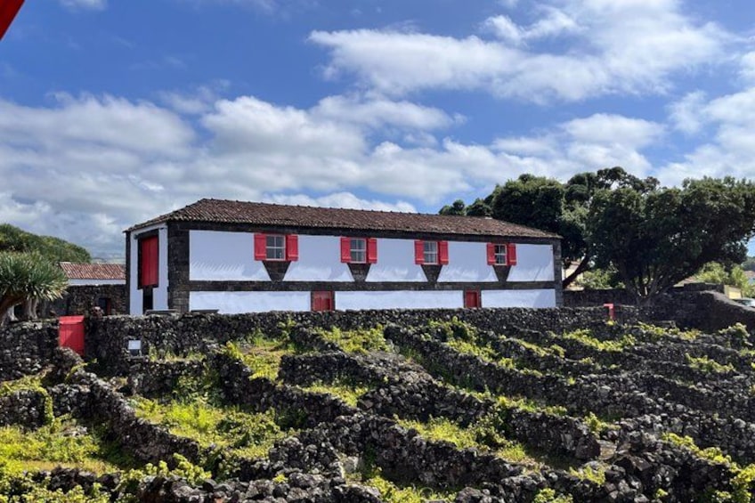 A white building with red shutters and a stone wall in the foreground. 2