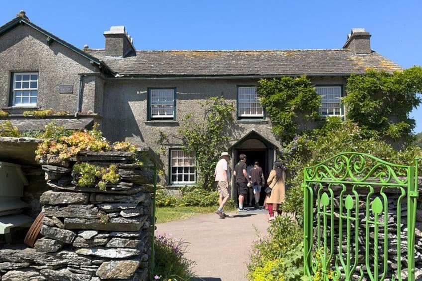 A stone house with a green gate, a stone wall, and a pathway. 4