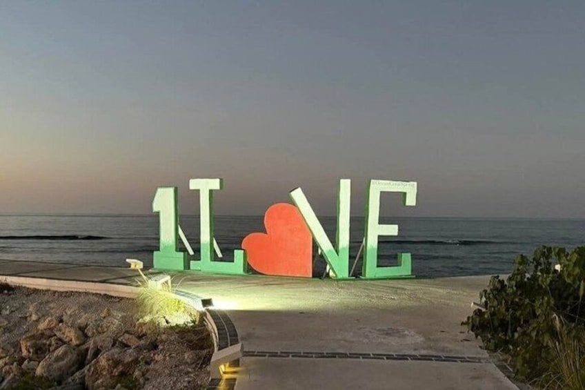 A beach with large illuminated letters spelling 'LOVE' and a heart symbol. 2