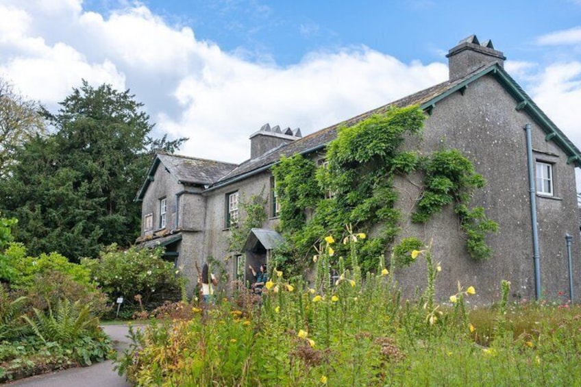 A stone house with ivy, surrounded by lush greenery and a pathway. 3