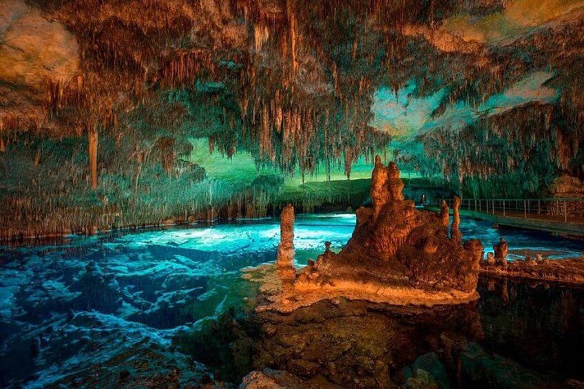 An underground cave with stalactites, a water pool, and a rocky outcrop. 3