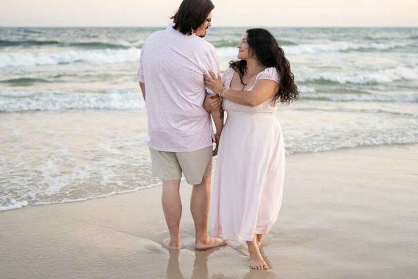 A couple standing on a beach with the ocean in the background. 3