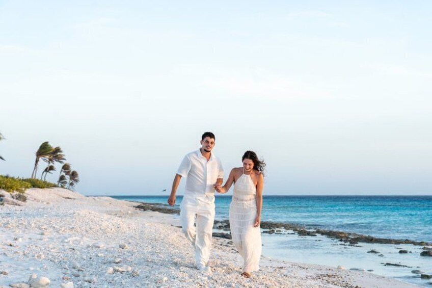A couple walking on a sandy beach with the ocean in the background. 1