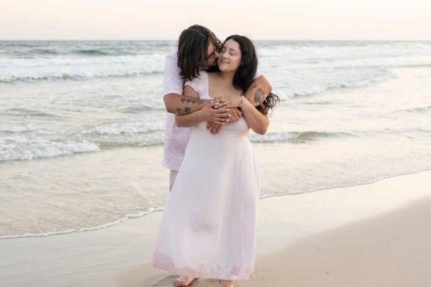 A couple embracing on a beach with ocean waves in the background. 2