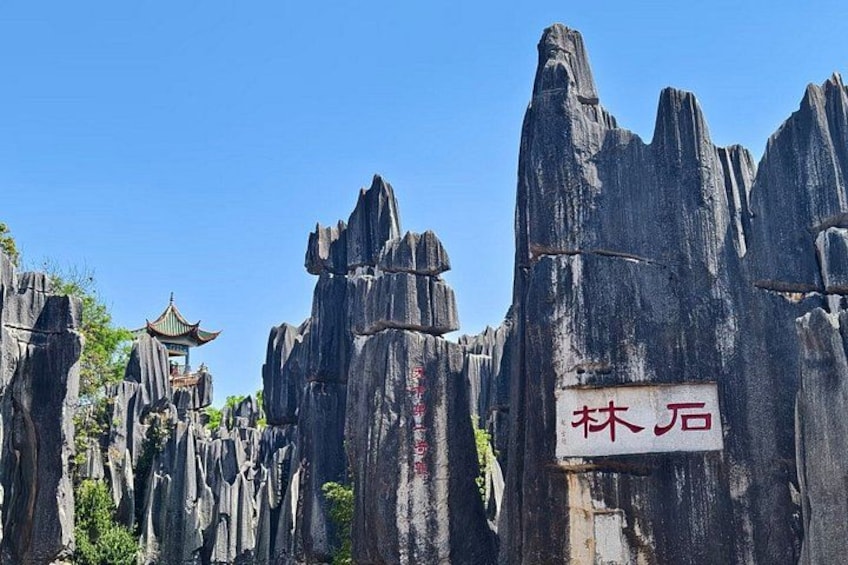 A rock formation with a pagoda and a sign with Chinese characters. 1