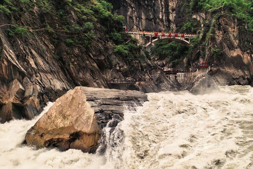 A waterfall cascading over a rock, a bridge, and a rocky cliff. 3