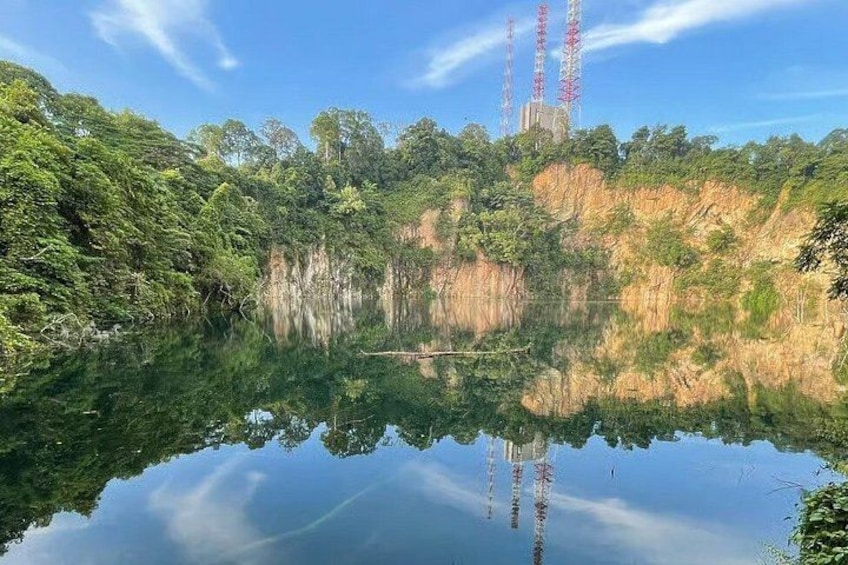 A calm lake with reflections of trees and a distant tower. 2