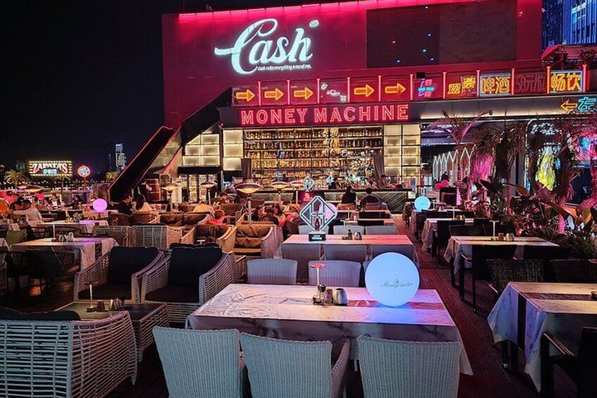 A casino with a neon sign, outdoor seating, and a money machine. 4