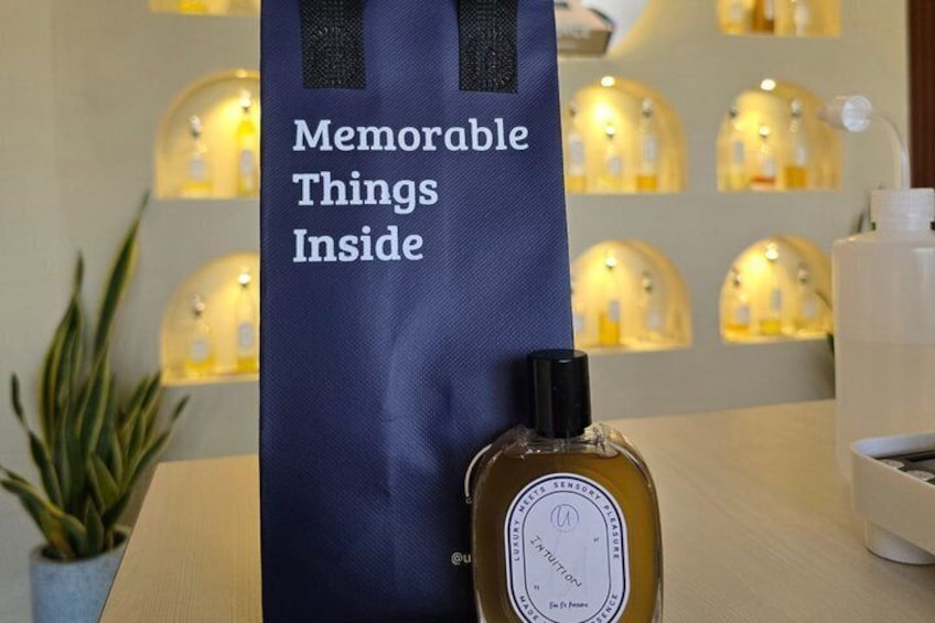 A blue bag with the text 'Memorable Things Inside' and a bottle of perfume on a table. 3