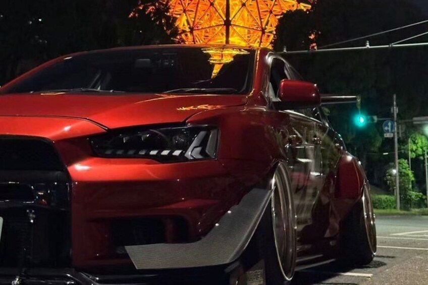 A red sports car parked at a traffic light. 1