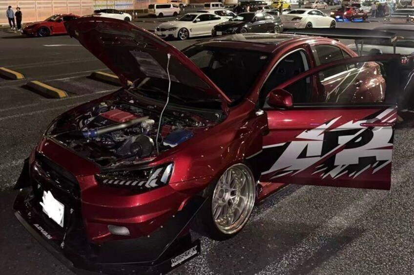 A red car with a modified engine bay and a large rear wing. 5