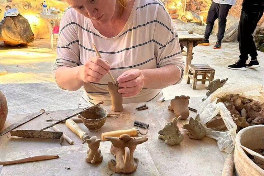 A person sculpting clay figures on a table. 3