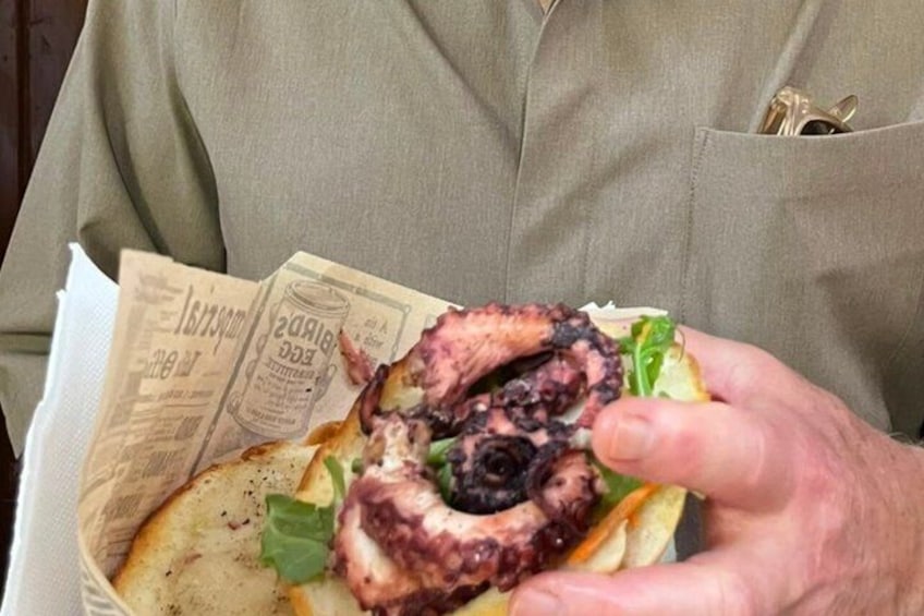 A person holding a sandwich with a piece of octopus. 1