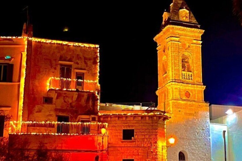 A historic building with a clock tower, illuminated by warm lights. 5