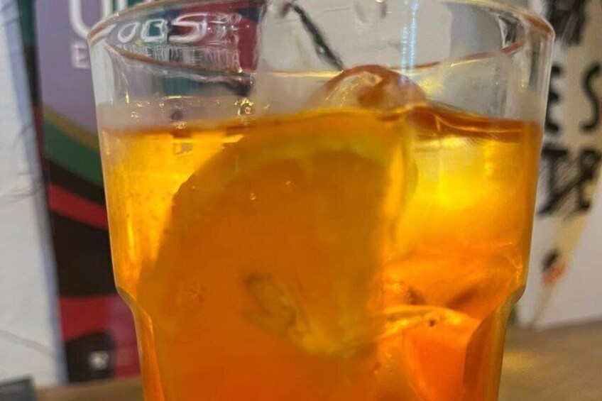A glass with a yellowish liquid and ice cubes. 2