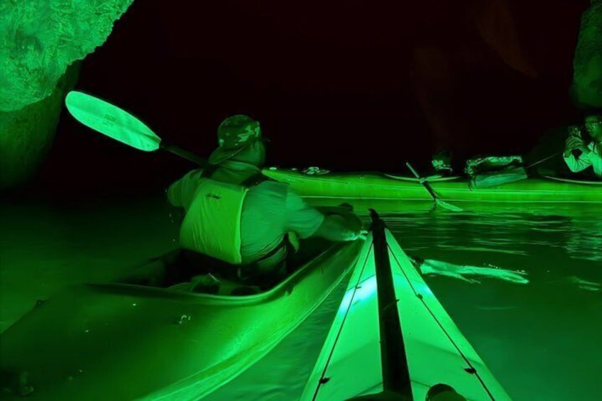 A person kayaking in a narrow waterway with a green light. 3
