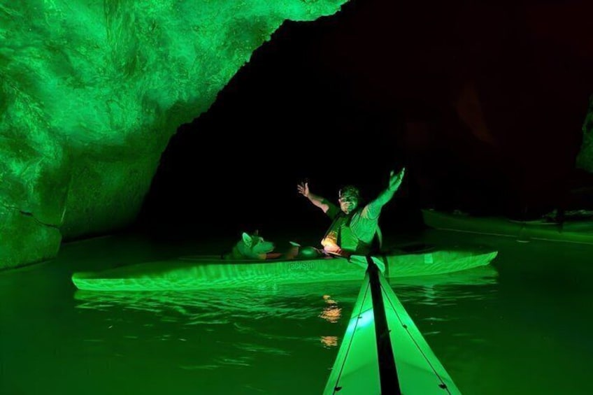 A person kayaking in a cave with green lighting. 4
