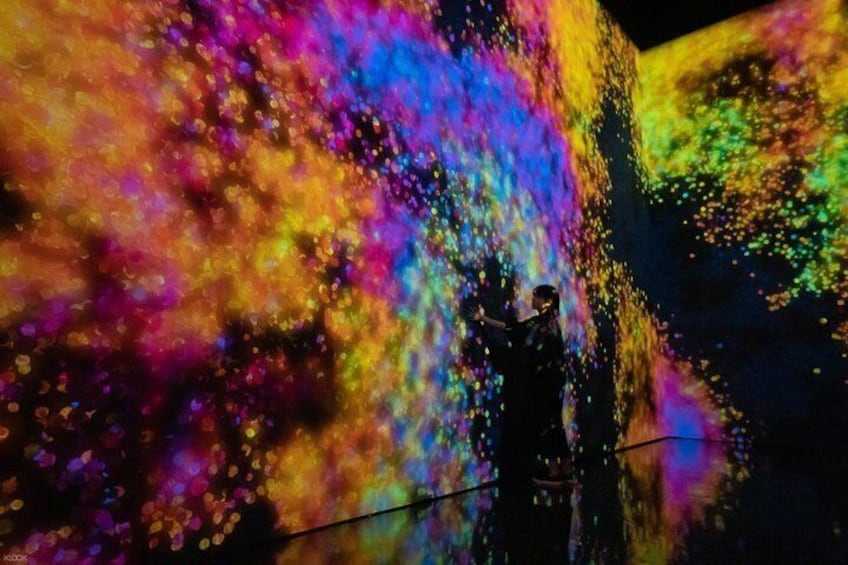 A person standing in front of a colorful light projection. 2
