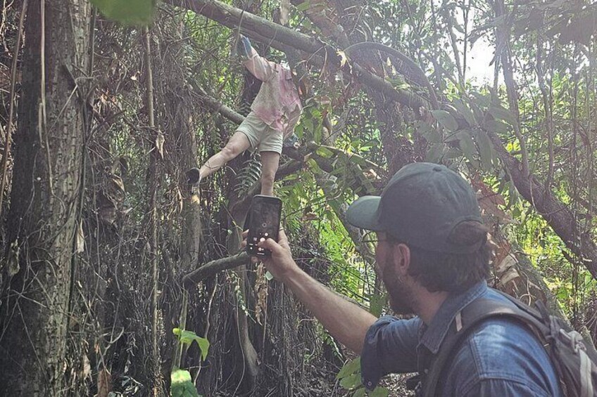 A person taking a photograph of another person climbing a tree. 2