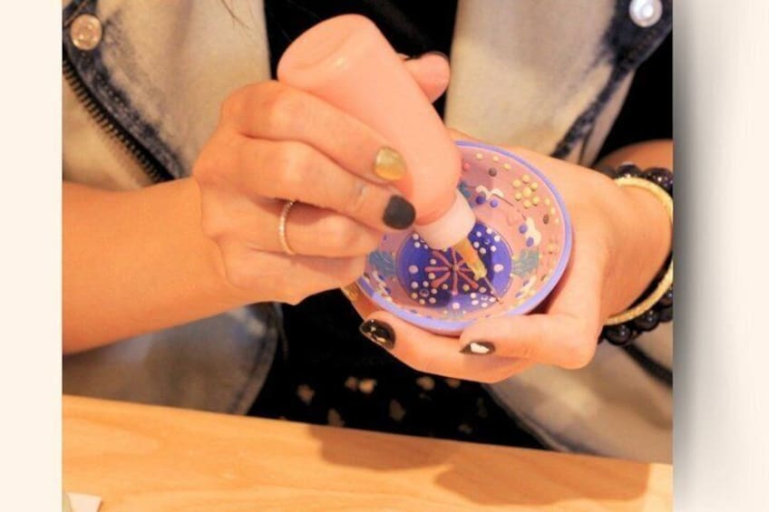 A person holding a small, colorful object with intricate designs. 1