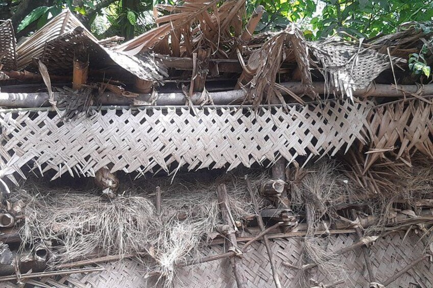 A traditional woven structure with a lattice design, surrounded by natural debris and branches. 2