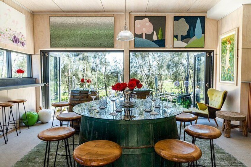 A round dining table with stools, surrounded by artwork, and a view of trees through large windows. 4