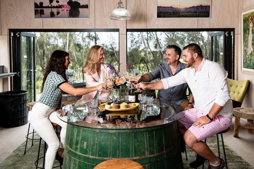 A group of people toasting with drinks around a barrel. 2