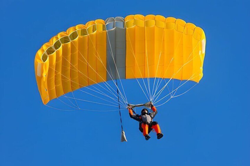 A person skydiving with a parachute against a clear blue sky. 5