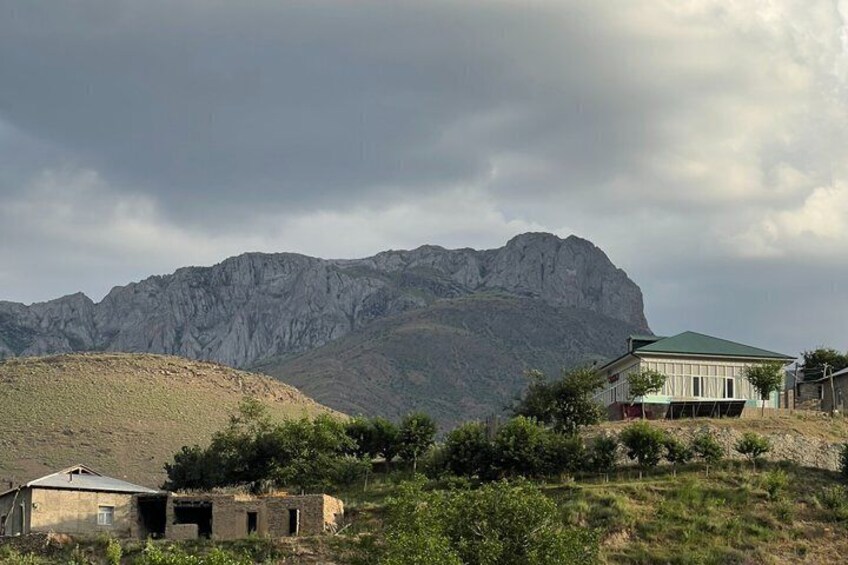 A mountainous landscape with a house and a smaller building in the foreground. 5