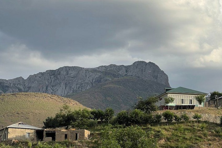 A mountainous landscape with a house and a smaller building in the foreground. 5