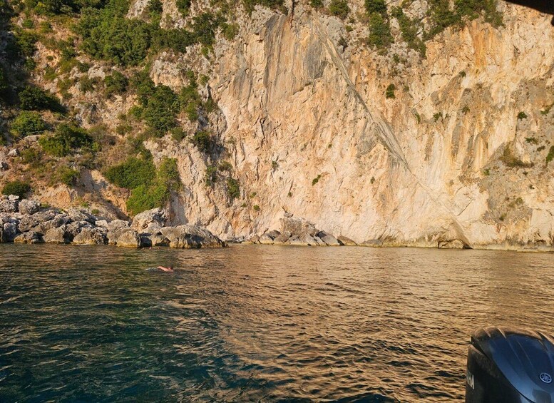A rocky coastline with clear water and a boat in the foreground. 2