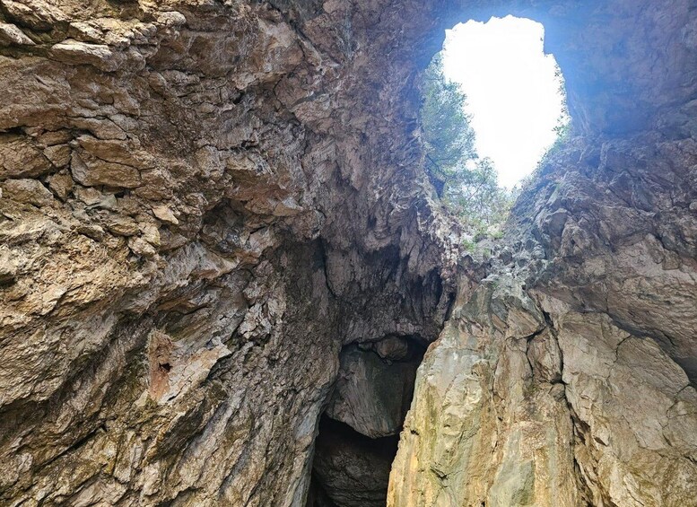 A rocky canyon with a narrow passageway and a visible sky through the top. 4