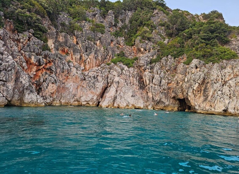 A rocky coastline with clear blue water and a cave entrance. 5